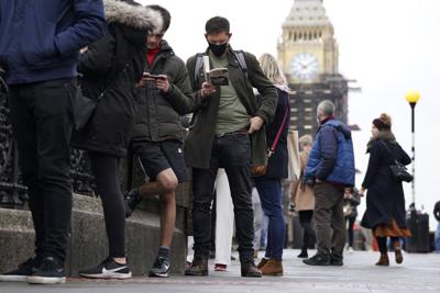 Un grupo de personas hace fila para ponerse la vacuna contra el coronavirus en Londres el 13 de diciembre del 2021.  (Kirsty O'Connor/PA via AP)