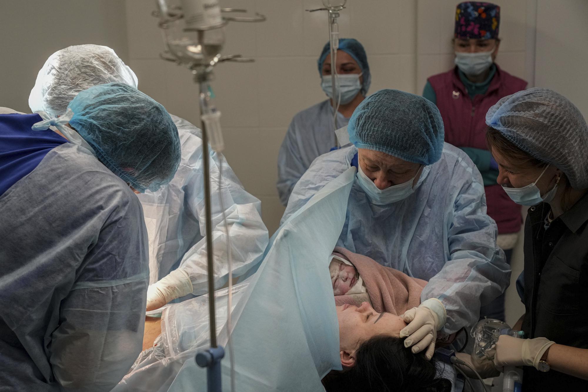 FILE - Medical workers hold newborn Alana close to her mother after a cesarean section at a hospital in Mariupol, Ukraine, March 11, 2022. Alana's mother had to be evacuated from another maternity hospital that was bombed by Russian forces and lost some of her toes. (AP Photo/Evgeniy Maloletka, File)