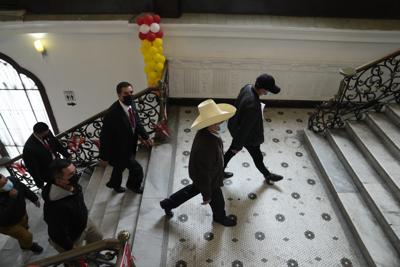 El candidato presidencial Pedro Castillo, con sombrero, se dirige a la sala donde dará una conferencia de prensa en la sede de su campaña en Lima, Perú, el martes 15 de junio de 2021.  (AP Foto/Martín Mejía)