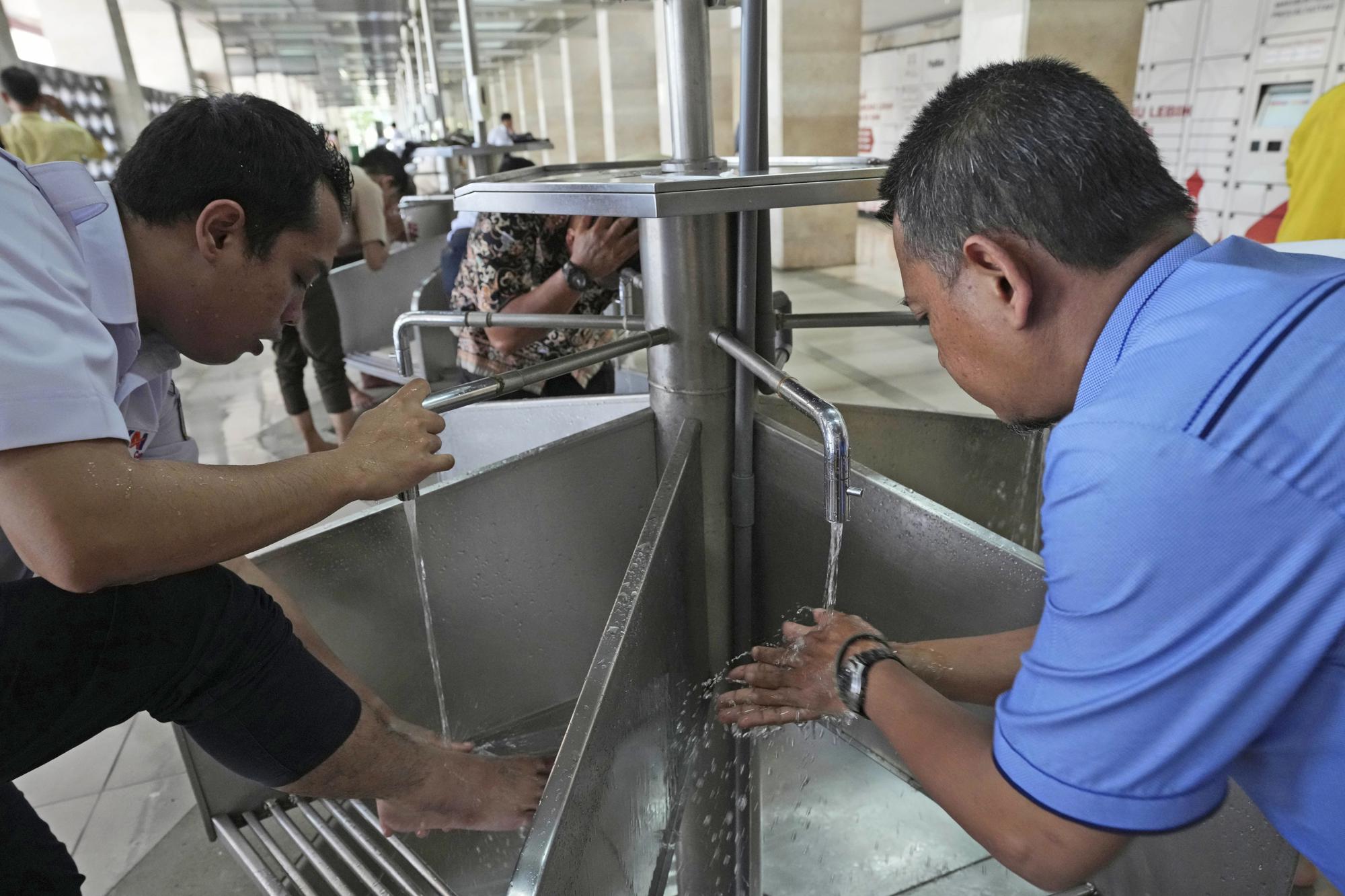 Muslim men wash before performing midday prayer at Istiqlal Mosque whose electricity partially comes from solar power in Jakarta, Indonesia, Wednesday, March 29, 2023. A major renovation in 2019 installed upwards of 500 solar panels on the mosque's expansive roof, now a major and clean source of Istiqlal's electricity. (AP Photo/Tatan Syuflana)