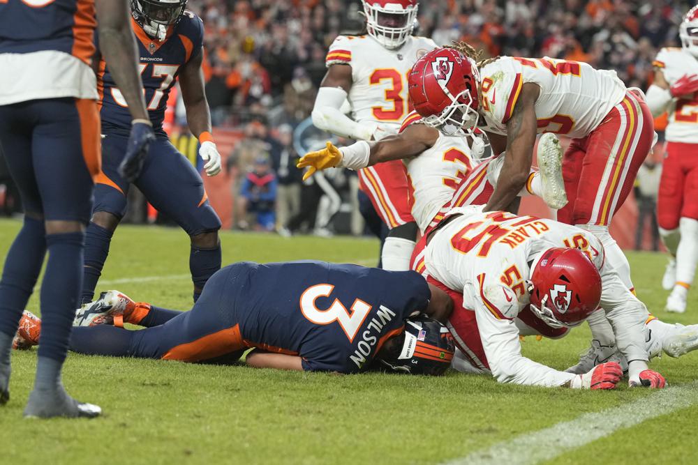 Denver Broncos quarterback Russell Wilson, right, goes down as he is tackled by Kansas City Chiefs defensive end Frank Clark (55) during the second half of an NFL football game Sunday, Dec. 11, 2022, in Denver. (AP Photo/David Zalubowski)