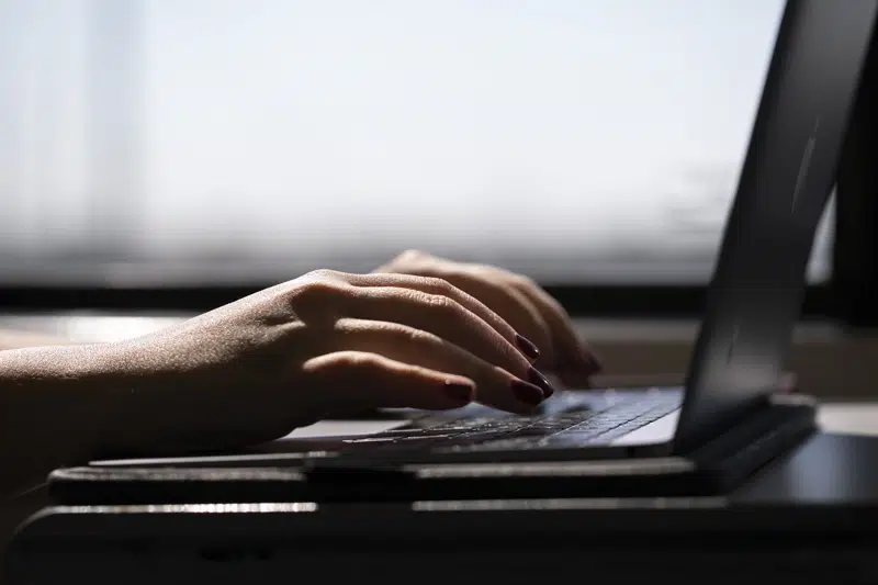 FILE - A woman types on a laptop while on a train in New Jersey, May 18, 2021. A trial of a four-day workweek in Britain, billed as the world's largest, has found that an overwhelming majority of the 61 companies that participated over six months last year will keep going with the shorter hours and that most employees were less stressed and burned out and had better work-life balance. (AP Photo/Jenny Kane, File)