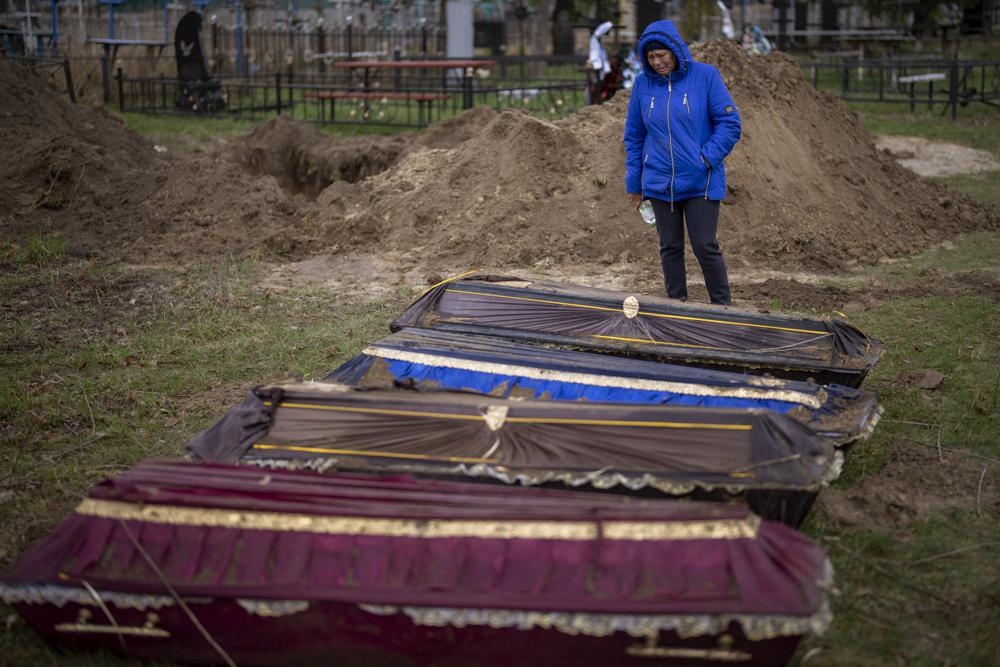 EL TÍTULO CORRIGE LA UBICACIÓN: Ira Slepchenko, de 54 años, llora junto a los ataúdes, uno de ellos con el cuerpo de su esposo Sasha Nedolezhko, de 43, durante una exhumación de civiles asesinados y enterrados en una fosa común en Mykulychi, Ucrania, el domingo 17 de abril. 2022. Los cuatro cuerpos en la tumba del pueblo fueron asesinados en la misma calle, el mismo día.  Sus ataúdes temporales estaban juntos en una tumba.  El domingo, dos semanas después de la desaparición de los soldados, los voluntarios los desenterraron uno por uno para llevarlos a una morgue para su investigación.  (Foto AP/Emilio Morenatti)
