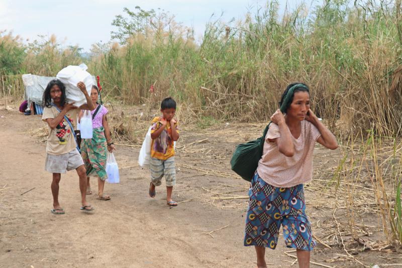 Displaced people from Myanmar carry donated lunch boxes to their tents along the Thai side of the Moei River in Mae Sot, Thailand on Feb. 5, 2022. Thailand has sent thousands of people fleeing escalating violence by Myanmar’s military back home despite the risk to their lives, and despite international refugee laws that forbid the return of people to countries where their lives may be in danger. They are now living in limbo, forced to ricochet between both sides of the river dividing the two countries as the fighting in their home villages rages and briefly recedes. (AP Photo)