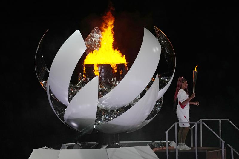 Naomi Osaka stands beside the Olympic flame after lighting it during the opening ceremony in the Olympic Stadium at the 2020 Summer Olympics, Friday, July 23, 2021, in Tokyo, Japan. (AP Photo/David J. Phillip)