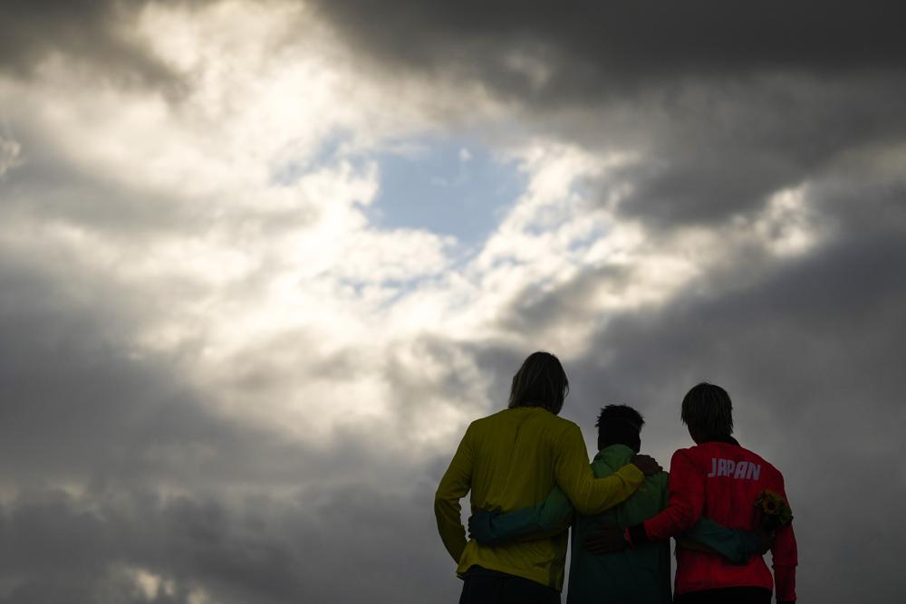 Brazil's Italo Ferreira, center, gold medal, Japan's Kanoa Igarashi, right, silver medal, and Australia's Owen Wright, bronze medal, pose for photographers in the men's surfing competition at the 2020 Summer Olympics, Tuesday, July 27, 2021, at Tsurigasaki beach in Ichinomiya, Japan. (AP Photo/Francisco Seco)