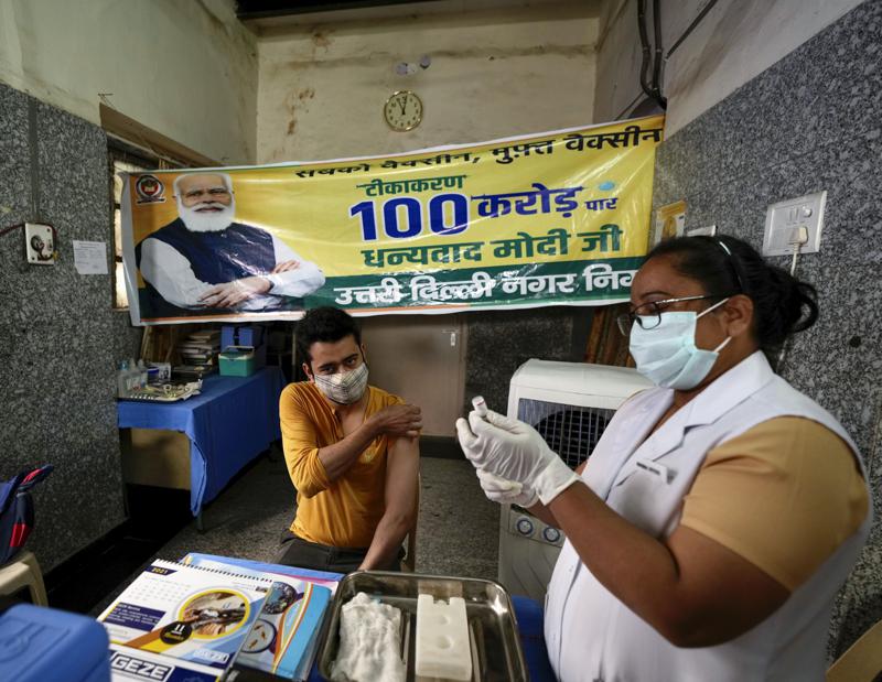 A health worker inoculates a man next to a banner thanking Prime Minister Narendra Modi for 1 billion doses of COVID-19 vaccine at a government hospital in New Delhi, India, Thursday, Oct. 21, 2021. India has administered 1 billion doses of COVID-19 vaccine, passing a milestone for the South Asian country where the delta variant fueled its first crushing surge this year. (AP Photo/Manish Swarup)
