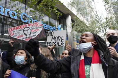 Personas sostienen carteles mientras se reúnen para protestar frente al Banco Standard and Chartered en Londres, Inglaterra, el viernes 29 de octubre de 2021. (AP Foto/Frank Augstein)