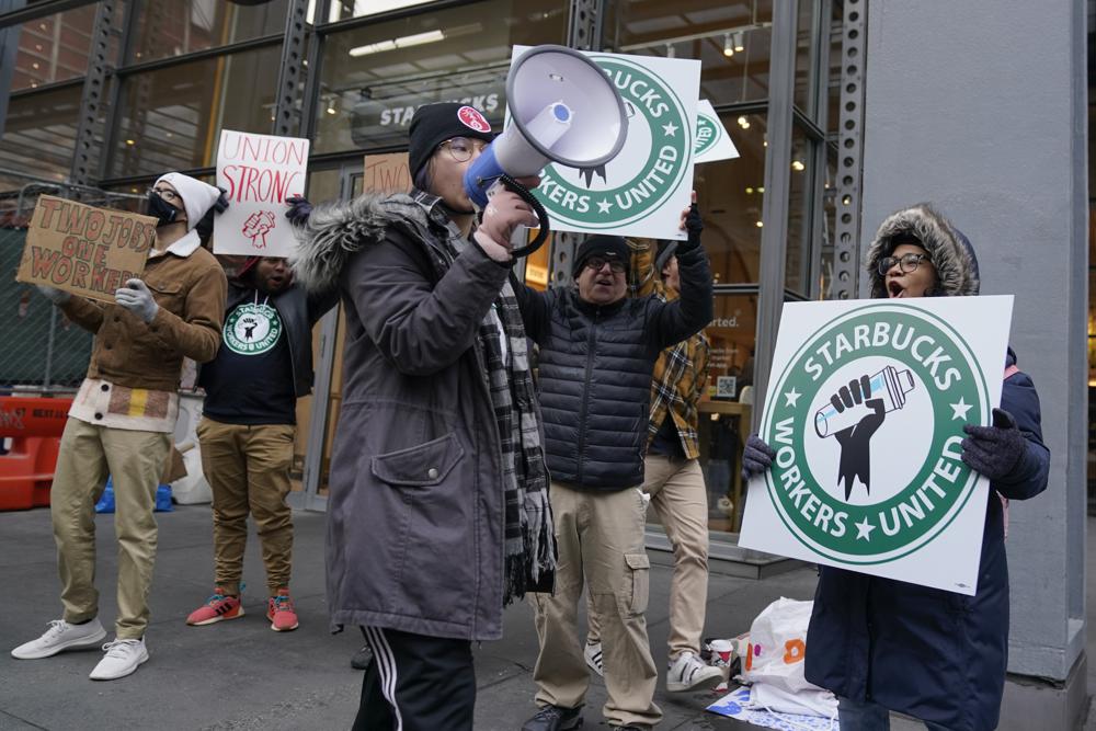 People chant and hold signs in front of a Starbucks in New York, Thursday, Nov. 17, 2022. Starbucks workers at more than 100 U.S. stores say they're going on strike Thursday in what would be the largest labor action since a campaign to unionize the company's stores began late last year. (AP Photo/Seth Wenig)