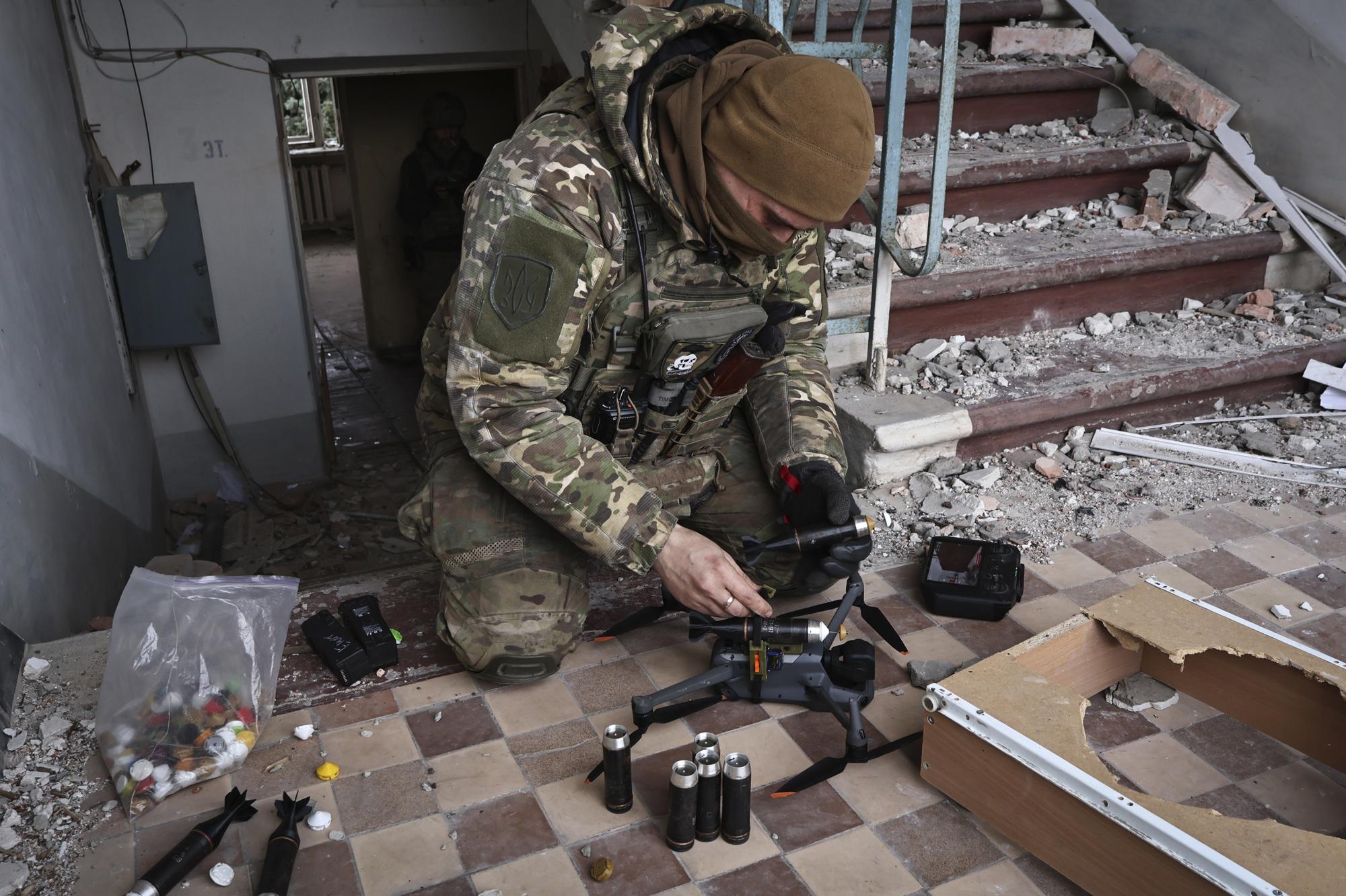 A Ukrainian soldier equips a drone with grenades in the area of the heaviest battles with the Russian invaders in Bakhmut, Donetsk region, Ukraine, Wednesday, March 15, 2023. (AP Photo/Roman Chop)