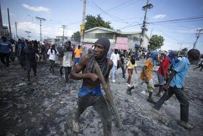 ARCHIVO _ Un manifestante lleva un pedazo de madera simulando un fusil durante una protesta en demanda de la renuncia del primer ministro Ariel Henry en Puerto Príncipe, Haití, el 3 de octubre del 2022.  (AP Foto/Odelyn Joseph)