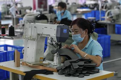 Trabajadoras portan mascarillas mientras cosen unos zapatos en una fábrica de equipo para hielo y nieve en Zhangjiakou, en la provincia de Hebei, China, el 15 de julio de 2021. (AP Foto/Andy Wong)