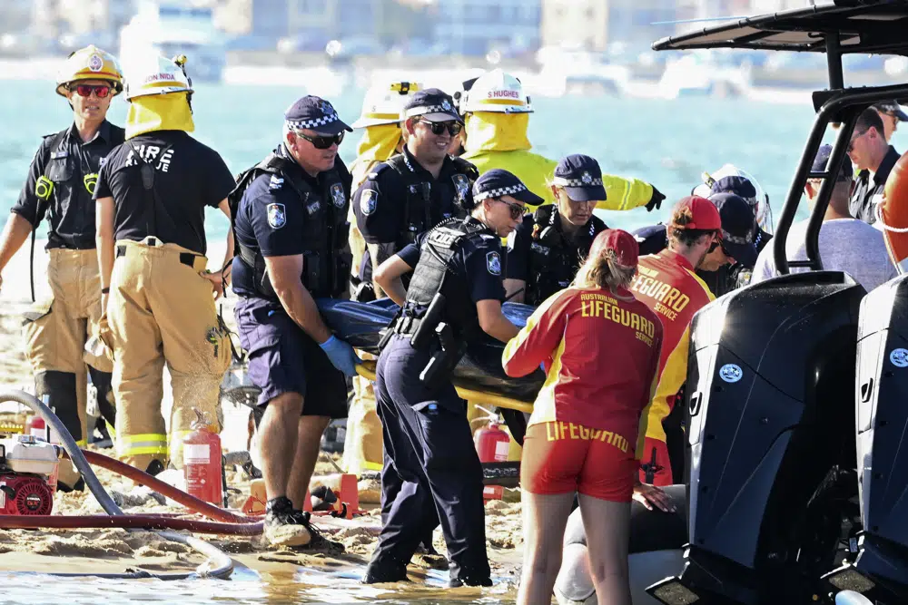 Los trabajadores de emergencia retiran un cuerpo de la escena de la colisión de un helicóptero cerca de Seaworld, en Gold Coast, Australia, el lunes 2 de enero de 2023. Dos helicópteros chocaron matando a varios pasajeros e hiriendo gravemente a otros en un accidente que atrajo ayuda de emergencia de los bañistas que disfrutaban el agua durante el verano austral.  (Imagen de Dave Hunt/AAP vía AP)