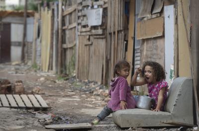 Una niña come de una cacerola en la calle en la favela Penha Brasil el 15 de mayo del 2021 en Sao Paulo. (AP Photo/Andre Penner, File)