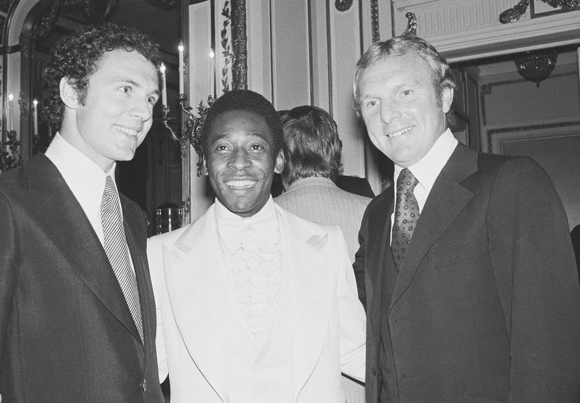 FILE - Soccer star Pele, center, poses with two other soccer greats: at left, Cosmos teammate and captain of the 1974 World Cup team from West Germany, Franz Beckenbauer, and Bobby Moore, captain of England's 1966 World Cup soccer team. The occasion was a dinner given for Pele, Sept. 27, 1977 in the Plaza Hotel in New York. (AP Photo/Richard Drew,file)
