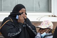 Witnesses of the aftermath react following a fatal fire in Philadelphia, on Wednesday, Jan. 5, 2022. Crews responded early morning and saw flames shooting from the second-floor front windows of the home. (Joe Lamberti /Camden Courier-Post via AP)
