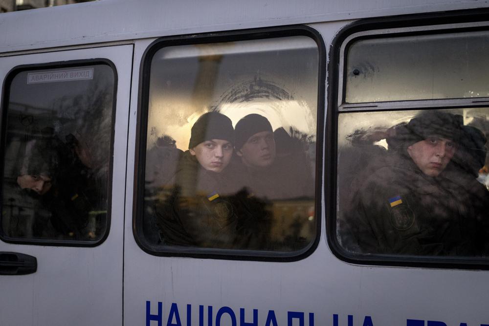 Members of National Guard of Ukraine look out of the window as they ride in a bus through the city of Kyiv, Monday, Feb. 14, 2022. More NATO troops headed to Eastern Europe and some nations worked to move their citizens and diplomats out of Ukraine on Monday, as Germany's chancellor made a last-ditch attempt to head off a feared Russian invasion that some warn could be just days away. (AP Photo/Emilio Morenatti)