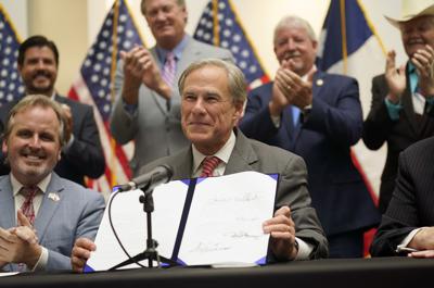 El gobernador de Texas, Greg Abbott, muestra la iniciativa SB1 que reforma la ley electoral estatal después de firmarla el martes 7 de septiembre de 2021. (AP Photo/LM Otero)