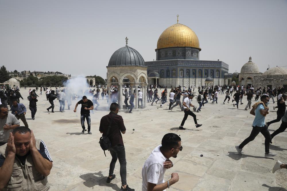 Palestinians run from sound bombs thrown by Israeli police in front of the Dome of the Rock shrine at al-Aqsa mosque complex in Jerusalem, Friday, May 21, 202, as aa cease-fire took effect between Hamas and Israel after 11-day war. (AP Photo/Mahmoud Illean)