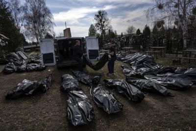 Trabajadores bajan cuerpos de civiles muertos de una camioneta en el cementerio de Bucha, en las afueras de Kiev, Ucrania, el jueves 7 de abril de 2022. (Foto AP/Rodrigo Abd)