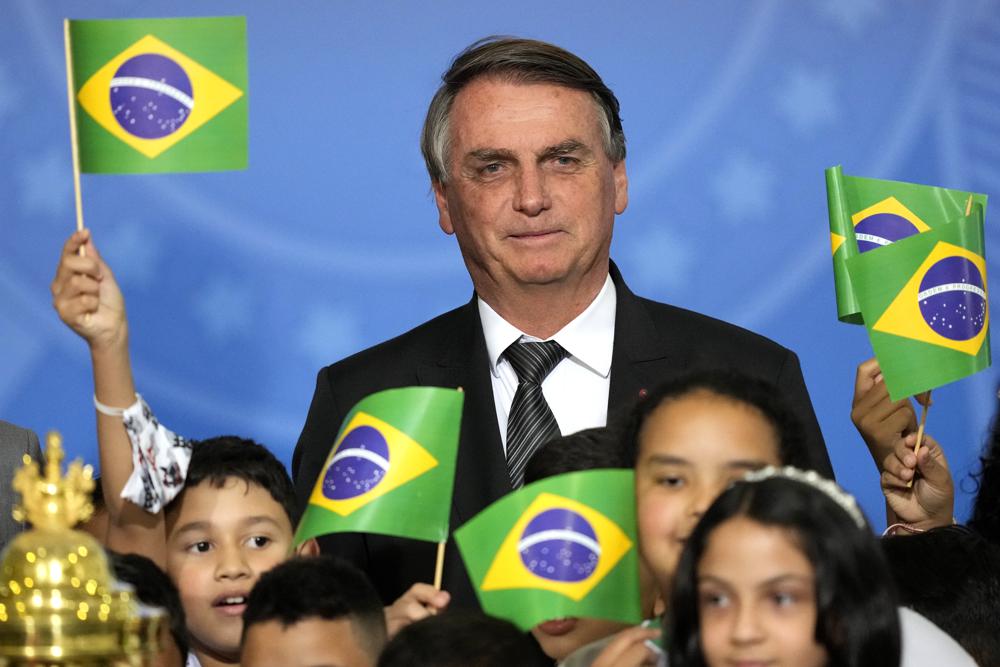 Brazil's President Jair Bolsonaro stands with a group of children during a ceremony to receive the reliquary containing the heart of Brazil's former emperor Dom Pedro I, at the Planalto Presidential Palace, in Brasilia, Brazil, Tuesday, Aug. 23, 2022. The heart arrived for display during the celebrations of Brazil's independence bicentennial on Sept. 7. (AP Photo/Eraldo Peres)