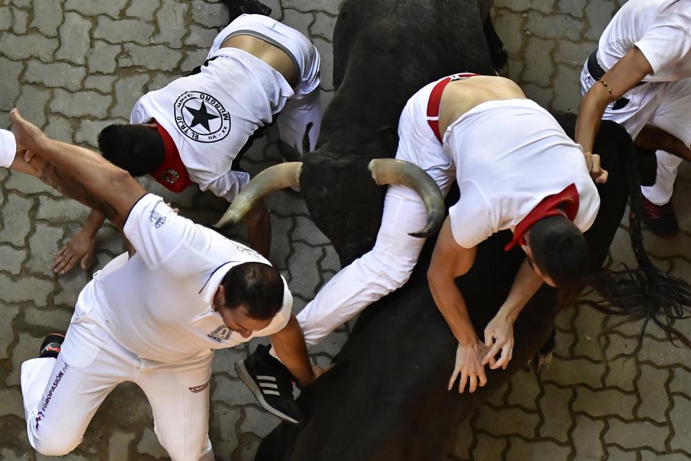 A fighting bull charges against runners during the running of the bulls at the San Fermin Festival in Pamplona, northern Spain, Monday, July 11, 2022. Revellers from around the world flock to Pamplona every year for nine days of uninterrupted partying in Pamplona's famed running of the bulls festival which was suspended for the past two years because of the coronavirus pandemic. (AP Photo/Alvaro Barrientos)