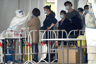 Un operario, equipado con un traje de protección, toma una muestra para un test de detección del coronavirus en un centro de pruebas en Beijing, el 23 de abril de 2022. (AP Foto/Mark Schiefelbein)