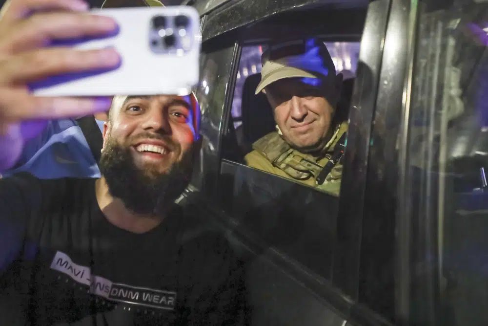 Yevgeny Prigozhin, the owner of the Wagner Group military company, right, sits inside a military vehicle posing for a selfie photo with a local civilian on a street in Rostov-on-Don, Russia, Saturday, June 24, 2023, prior to leaving an area of the headquarters of the Southern Military District. Kremlin spokesman Dmitry Peskov said that Prigozhin's troops who joined him in the uprising will not face prosecution and those who did not will be offered contracts by the Defense Ministry. After the deal was reached Saturday, Prigozhin ordered his troops to halt their march on Moscow and retreat to field camps in Ukraine, where they have been fighting alongside Russian troops. (AP Photo)