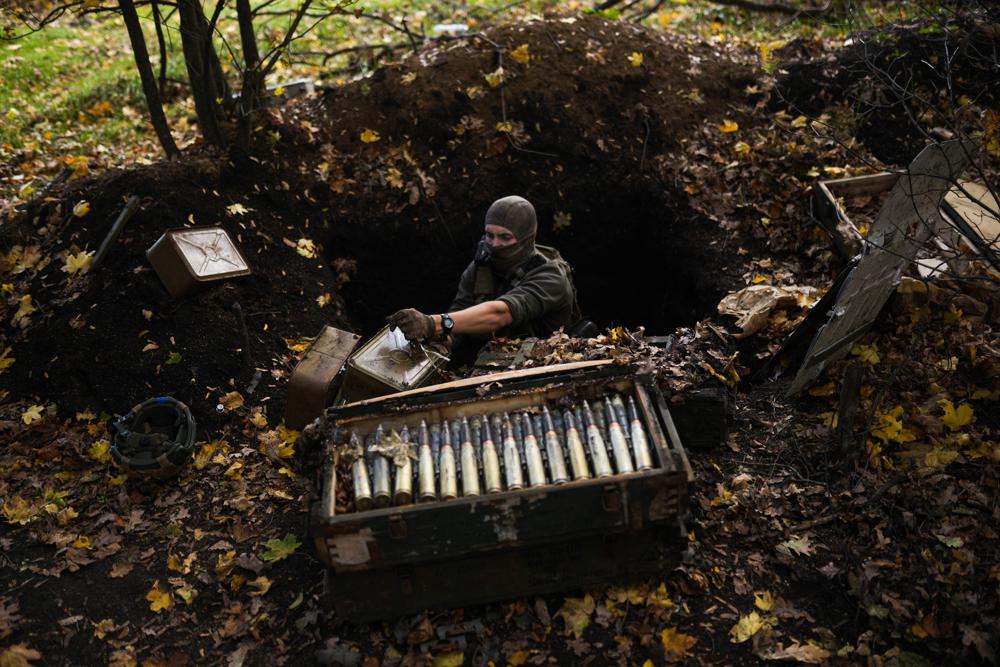 Un soldado ucraniano toma municiones que abandonaron las fuerzas rusas en su retirada mientras su equipo retira minas, el jueves 13 de octubre de 2022, cerca del poblado de Grakove, Ucrania. (AP Foto/Francisco Seco)