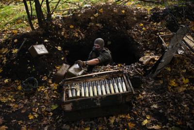 Un soldado ucraniano toma municiones que abandonaron las fuerzas rusas en su retirada mientras su equipo retira minas, el jueves 13 de octubre de 2022, cerca del poblado de Grakove, Ucrania. (AP Foto/Francisco Seco)
