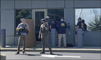 In this image taken from FOX19 Cincinnati video, FBI officials gather outside the FBI building in Cincinnati, Thursday, Aug. 11, 2022. An armed man decked out in body armor tried to breach a security screening area at the FBI field office in Ohio on Thursday, then fled and exchanged gunfire in a standoff with law enforcement, authorities said. (FOX19 Cincinnati via AP)