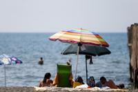 People enjoy a day at the beach, in Ostia, in the outskirts of Rome, Saturday, Aug. 14, 2021. A heat wave settled over southern Europe threatened temperatures topping 45 degrees Celsius (113 degrees Fahrenheit) in many parts of the Iberian Peninsula on Saturday while Italian authorities expanded to 16 the number of cities on red alert for conditions that can pose a health risk to the elderly and vulnerable. (Cecilia Fabiano/LaPresse via AP)