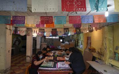 Artesanos hacen "papel picado", decoraciones tradicionales utilizadas desde hace mucho tiempo en los altares por el Día de Muertos, el jueves 27 de octubre de 2022, en Xochimilco, un distrito de la Ciudad de México. (AP Foto/Eduardo Verdugo)