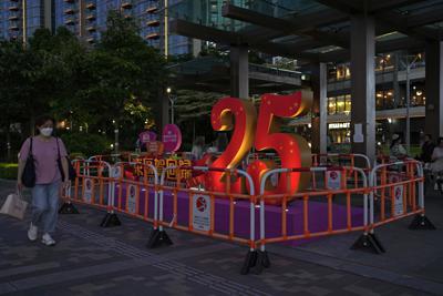 ARCHIVO -  Una mujer pasa junto a una escultura para celebrar el 25 aniversario de la entrega de Hong Kong a China, el viernes 24 de junio de 2022. (AP Foto/Kin Cheung, Archivo)