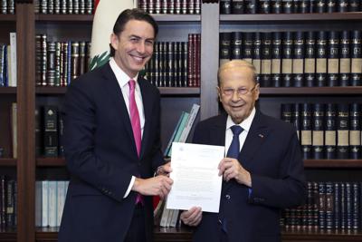 En esta foto dada a conocer por el fotógrafo oficial del gobierno libanés Dalati Nohra, el presidente libanés Michel Aoun, derecha, recibe de manos de enviado estadounidense para energía Amos Hochstein una copia del acuerdo mediado por Washington para la demarcación de la frontera marítima entre Líbano e Israel, en Beirut, el 27 de octubre del 2022. (Dalati Nohra via AP)