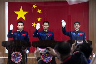 Desde la izquierda, los astronautas chinos Tang Hongbo, Nie Haisheng y Liu Boming saludan a los reporteros un día antes de viajar hacia la estación espacial china Tianhe o Armonía Celestial, el 16 de junio de 2021 en Jiuquan, China. (AP Foto/Ng Han Guan)