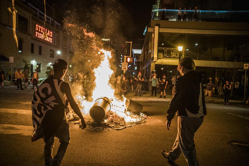 Protesters set a dumpster on fire after a shooting on Thursday, June 3, 2021 in Minneapolis.  Crowds vandalized buildings and stole from businesses in Minneapolis’ Uptown neighborhood after officials said a man wanted for illegally possessing a gun was fatally shot by authorities.  (Richard.Tsong-Taatari/Star Tribune via AP)