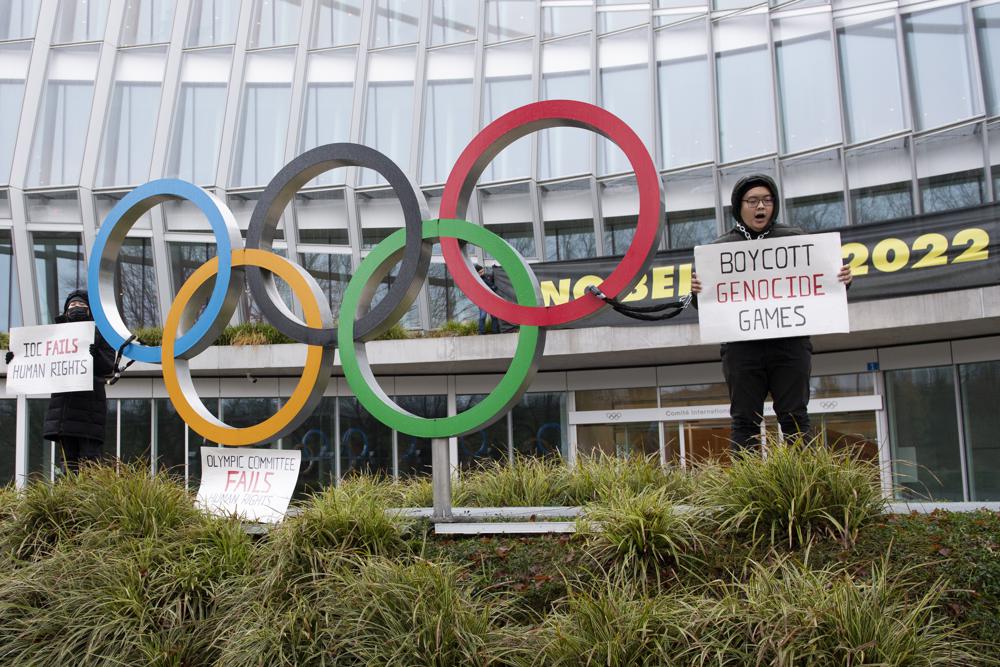 Manifestantes sostienen letreros durante una protesta contra la realización de los Juegos Olímpicos de Invierno de Beijing de 2022, frente a la sede del Comité Olímpico Internacional, en Lausana, Suiza, el sábado 11 de diciembre de 2021. (Jean-Guy Python/Keystone vía AP)