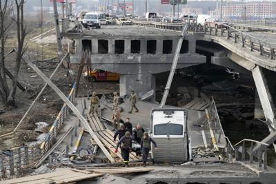 Soldados ucranianos cargan el cuerpo de un civil que murió a manos de las fuerzas rusas por un puente destruido en Irpín, el jueves 31 de marzo de 2022, cerca de Kiev, Ucrania. (AP Foto/Efrem Lukatsky)