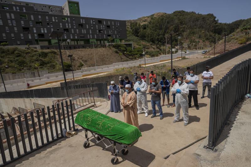 Ceuta residents and migrants perform a funeral prayer on a Moroccan teenager in the muslim cemetery of Ceuta, Saturday, May 22, 2021. The young man died on Monday 17 trying to swim across the border from Morocco to Spain's North Africa enclave together with thousands of other migrants. (AP Photo/Bernat Armangue)