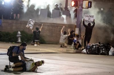 ARCHIVO - En esta foto de archivo del 30 de mayo de 2020, la gente ayuda a un manifestante después de que recibió un disparo de bala de goma debajo de la autopista Interestatal 35 en Austin, Texas, mientras protestaba por la muerte de George Floyd. El Concejo Municipal de Austin aprobó el jueves 17 de febrero de 2022 pagar un total combinado de $ 10 millones a dos personas heridas cuando los oficiales dispararon balas de frijoles contra multitudes durante las protestas de justicia social de 2020, incluido un estudiante universitario que sufrió daño cerebral. (Ricardo B. Brazziell/Austin American-Statesman vía AP, Archivo)