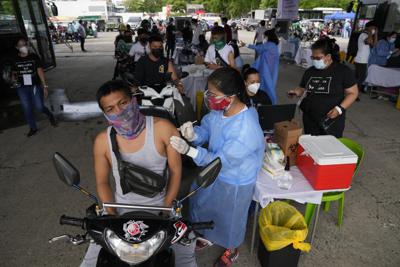 Un conductor de motocicleta recibe una dosis de la vacuna contra el COVID-19 desarrollada por la farmacéutica china Sinovac en un puesto de vacunación en Manila, Filipinas, el 22 de junio de 2021. (AP Foto/Aaron Favila)