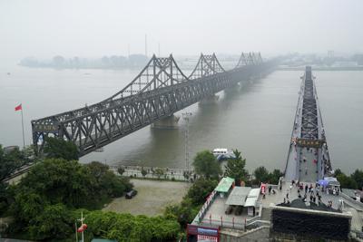 ARCHIVO - Visitantes caminan por el Puente Roto del río Yalu, a la derecha, junto al Puente de la Amistad, que conecta China y Corea del Norte, en Dadong, en la provincia nororiental china de Liaoning, el 9 de septiembre de 2017. (AP Foto/Emily Wang, Archivo)