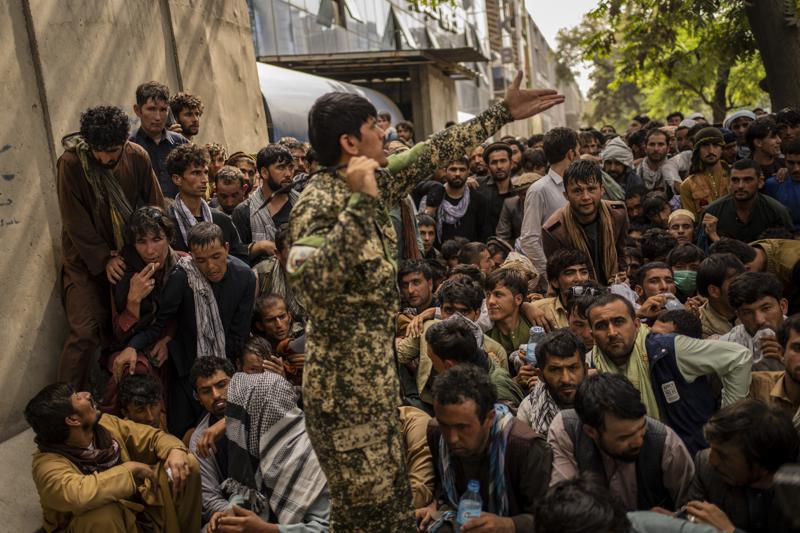 Archivo - En esta fotografía de archivo del domingo 12 de septiembre de 2021, los afganos esperan frente a un banco mientras intentan retirar dinero en Kabul, Afganistán.  Con los activos afganos congelados en Estados Unidos y el mundo reacio a reconocer a los talibanes, el sistema bancario del país se ha detenido.  Los salarios impagos y una crisis humanitaria en ciernes también ejercen más presión sobre el nuevo gobierno talibán, sin una salida clara.  (Foto AP / Bernat Armangue, archivo)