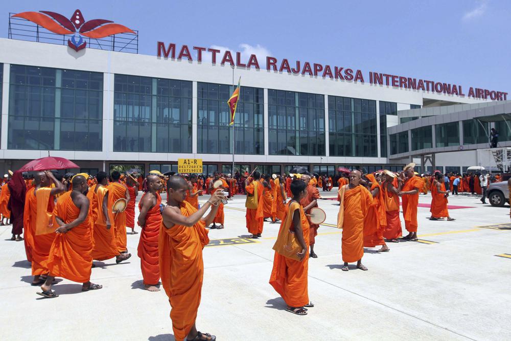 FILE - Sri Lankan Buddhist monks wait for the arrival of President Mahinda Rajapaksa at the Mattala Rajapaksa International Air Port in Mattala, Sri Lanka, Monday, March 18, 2013. The Chinese-funded airport built in the president’s hometown away from most of the country’s population is so barely used that elephants have been spotted wandering on its tarmac. (AP Photo/Sanka Gayashan, File)
