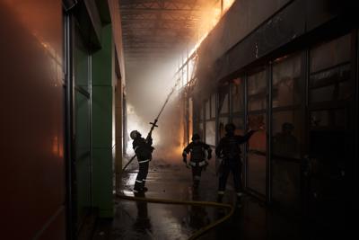 Bomberos intentan extinguir un incendio en una tienda luego de un bombardeo ruso en Járkiv, Ucrania, el viernes 22 de abril de 2022. (AP Foto/Felipe Dana)