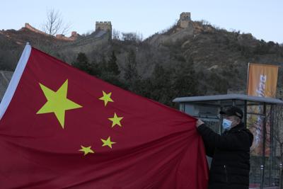 Un visitante con una bandera china en la Gran Muralla China en las afueras de  Beijing, el 8 de febrero del 2022. (Foto AP/Ng Han Guan)
