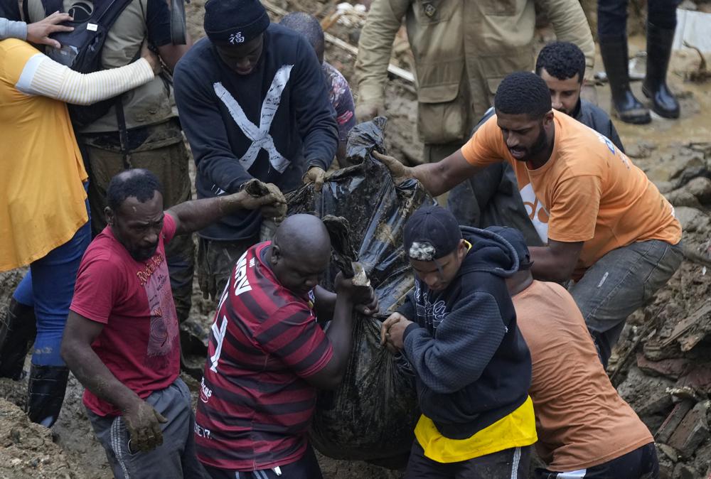Residentes y socorristas recuperan un cadáver en una zona afectada por aludes de tierra en Petrópolis, Brasil, el miércoles 16 de febrero de 2022. Lluvias extremadamente fuertes provocaron aludes e inundaciones en una región montañosa del estado de Río de Janeiro, matando a varias personas, informaron las autoridades. (AP Foto/Silvia Izquierdo)