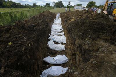 Un equipo forense entierra a un grupo de migrantes que murieron tratando de cruzar la brecha del Darién, en una fosa común en el cementerio de Guayabillo en Agua Fría, Panamá, el jueves 30 de septiembre de 2021. (Foto AP/Arnulfo Franco)