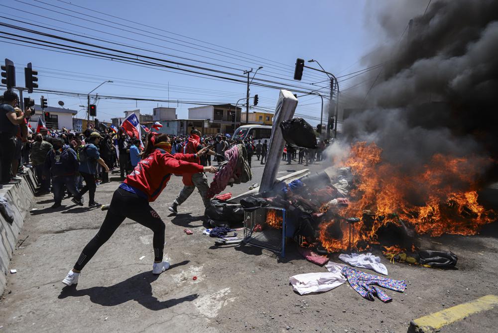 Residentes queman carpas y artículos pertenecientes a migrantes venezolanos y colombianos durante una marcha contra la migración irregular, en Iquique, Chile, el sábado 25 de septiembre de 2021. (Foto AP / Ignacio Muñoz)